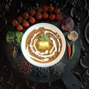 Bowl of home-made dal curry with cream, surrounded by tomatoes and spices