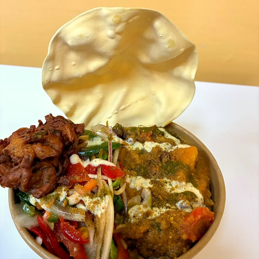 Curry rice bowl with salad, onion pakora and a papadam