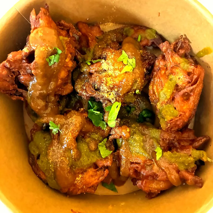 Crispy onion pakora in a takeaway bowl
