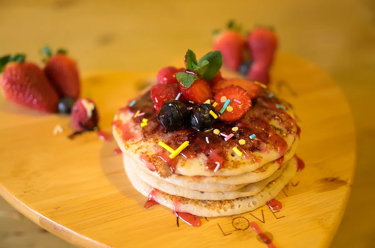 Stack of small sweet pancakes topped with berries