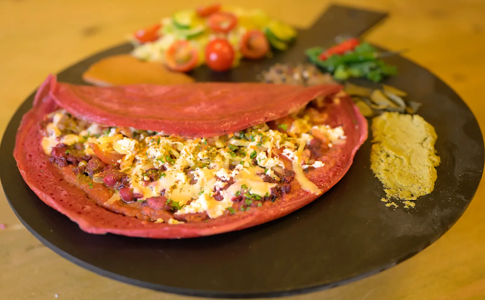 Pink beetroot Indian pancake on a serving board with salad and chutney